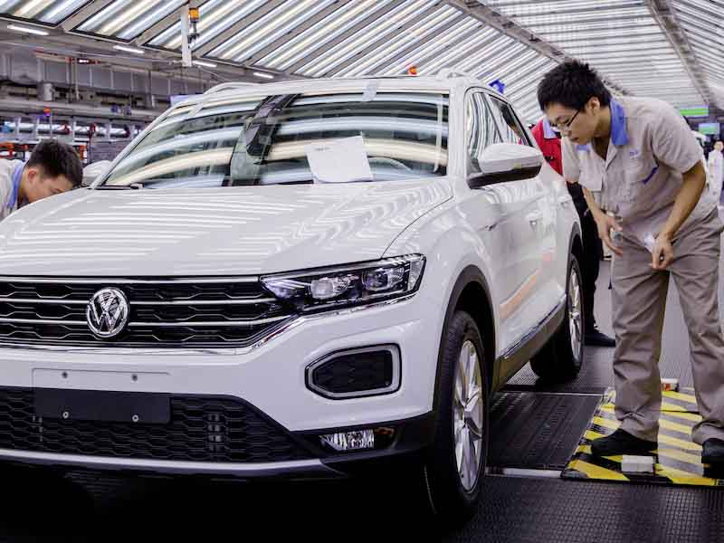 man looking at car in a factory