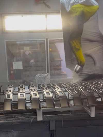 Large scale robot applying liquid paint to automotive components with a bell applicator.
