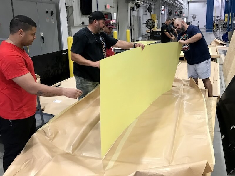 A team of maintenance workers with the 571st Commodities Maintenance Squadron Advanced Metal Finishing Facility, inspect a piece of sheet metal for defects at Robins Air Force Base, Georgia, Aug. 20, 2023. The United States Navy Fleet Readiness Center East requested the WR-ALC perform a one-time only chemical milling and anodizing process for 15 Navy H-53 helicopter skins. (U.S. Air Force photo by Danny Walters)