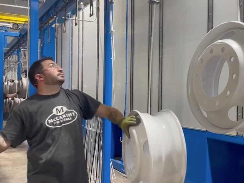 man hanging tire rims on coating line