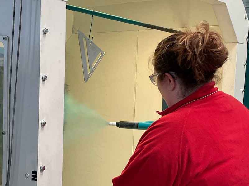 person spraying powder coating